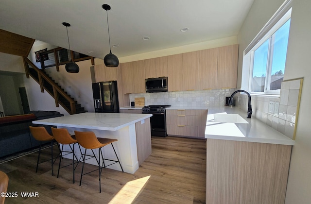 kitchen with a sink, modern cabinets, black appliances, and light brown cabinets