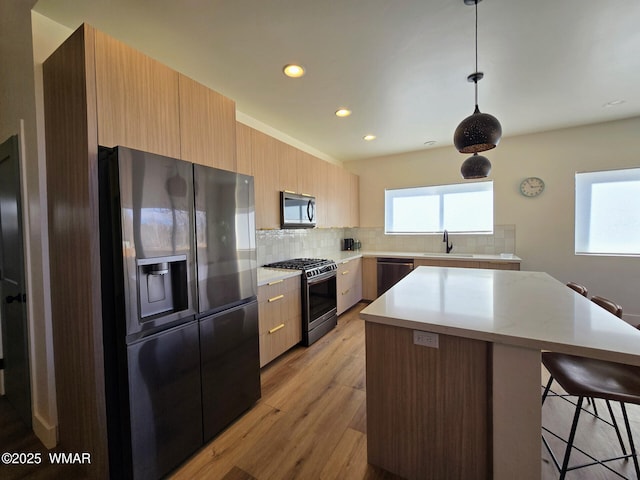 kitchen with a sink, decorative backsplash, stainless steel appliances, a kitchen breakfast bar, and a center island