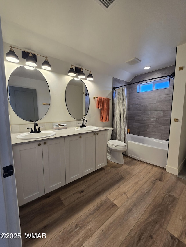 bathroom featuring a sink, toilet, wood finished floors, and shower / bath combo