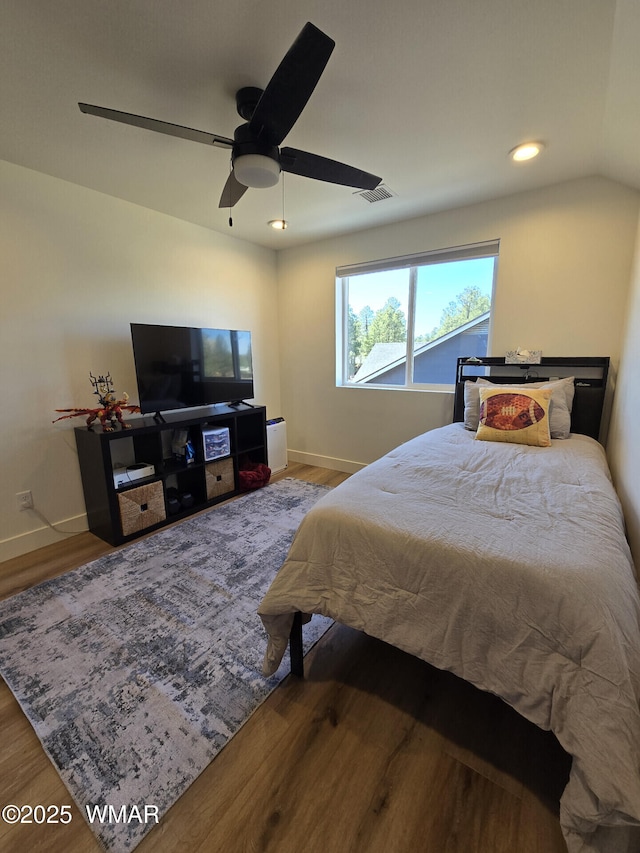 bedroom featuring visible vents, a ceiling fan, baseboards, and wood finished floors