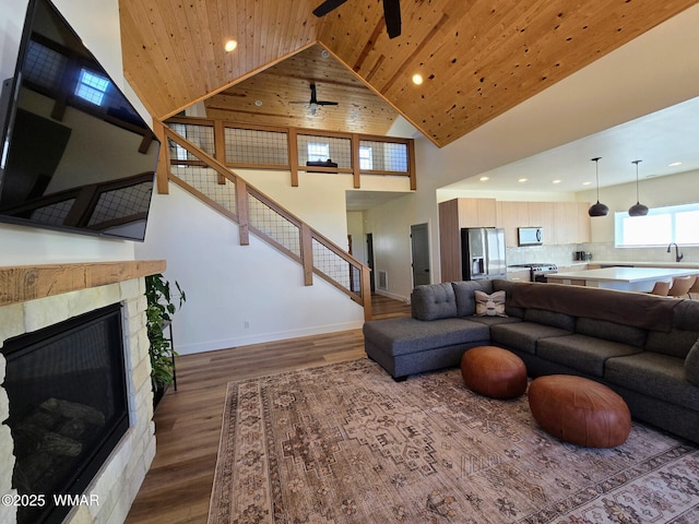 living area featuring stairway, wood finished floors, high vaulted ceiling, a fireplace, and wood ceiling