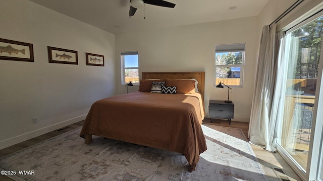 bedroom featuring access to outside, multiple windows, baseboards, and wood finished floors