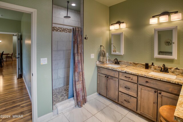 full bathroom featuring tiled shower, a sink, and double vanity