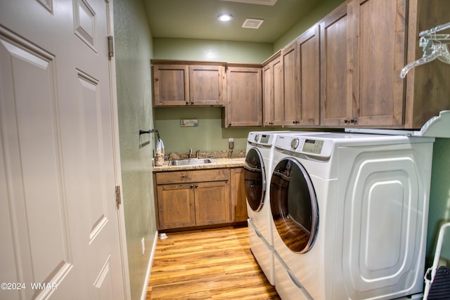 laundry room featuring recessed lighting, cabinet space, light wood-style floors, a sink, and separate washer and dryer