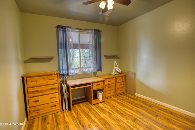 home office with light wood finished floors, a ceiling fan, and baseboards