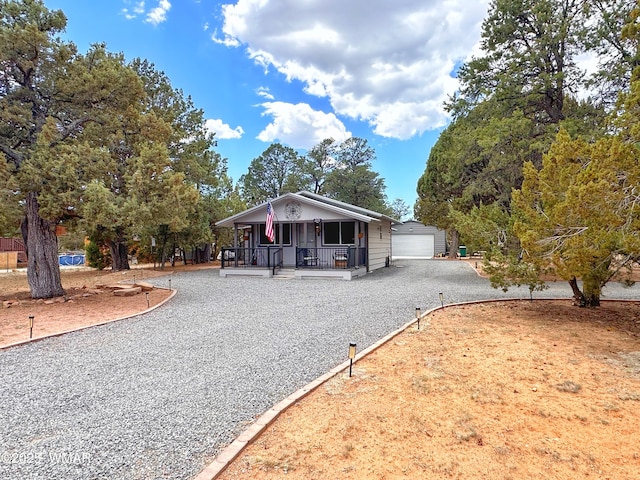 2872 Mustang Trl, Overgaard, AZ 85933 - view of front of house featuring covered porch, a garage, gravel driveway, and an outbuilding