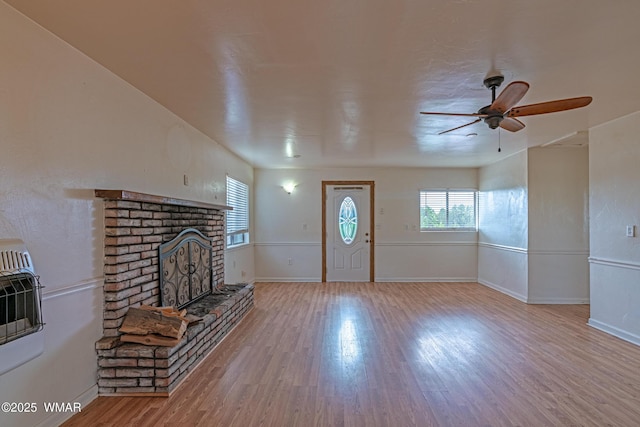 8460 Powells Ln, Show Low, AZ 85901 - unfurnished living room featuring wood finished floors, a ceiling fan, a brick fireplace, and baseboards