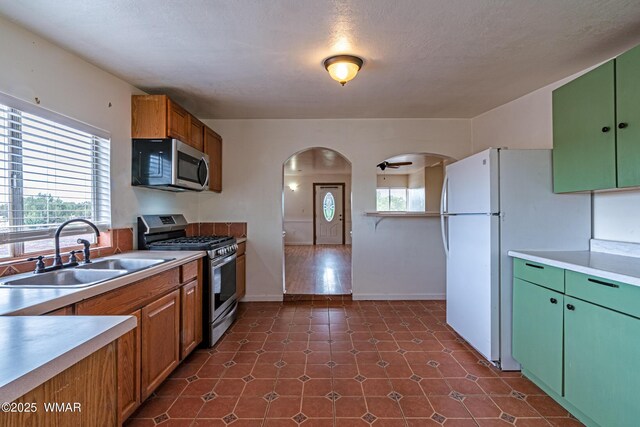 8460 Powells Ln, Show Low, AZ 85901 - kitchen featuring appliances with stainless steel finishes, a sink, arched walkways, and light countertops