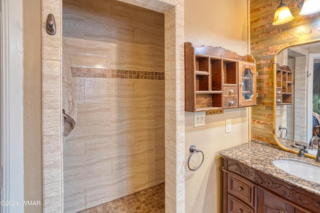 bathroom with a textured wall, a walk in shower, and vanity