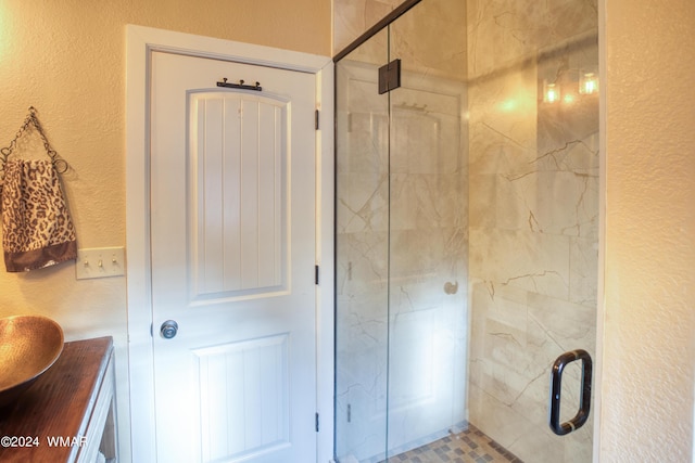 full bath featuring a textured wall, a shower stall, and vanity