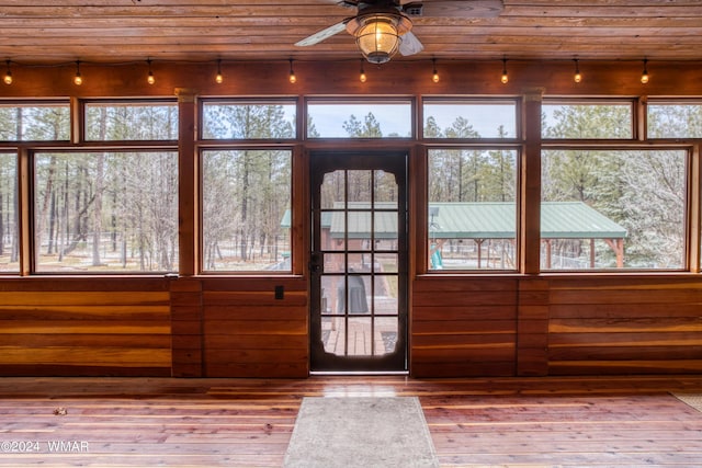 entryway featuring light wood finished floors, wood ceiling, a ceiling fan, and wood walls