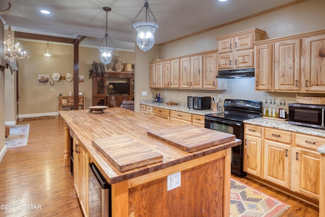 kitchen featuring stainless steel microwave, black electric range oven, a center island, under cabinet range hood, and pendant lighting