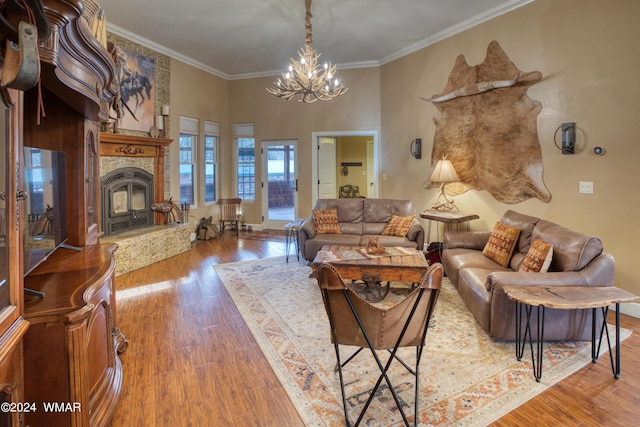 living area featuring a towering ceiling, a premium fireplace, ornamental molding, wood finished floors, and a chandelier