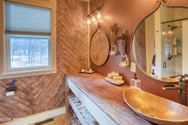 bathroom with a stall shower, visible vents, a textured wall, and vanity