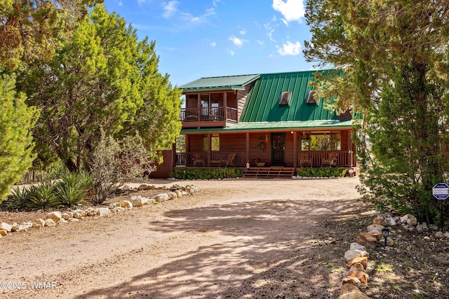view of front of house featuring a porch, dirt driveway, and metal roof