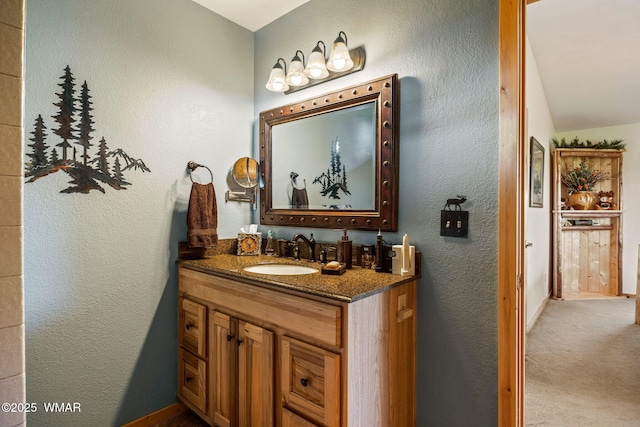 bathroom with vanity, a textured wall, and baseboards