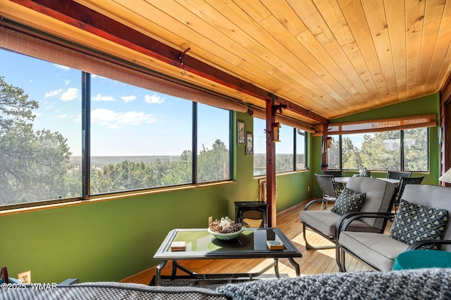 sunroom / solarium with lofted ceiling, wood finished floors, an outdoor living space, baseboards, and outdoor dining area