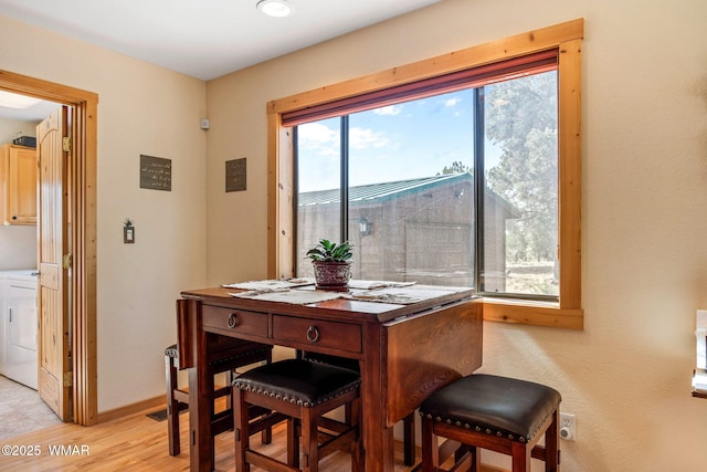 dining area featuring separate washer and dryer, baseboards, and light wood-type flooring