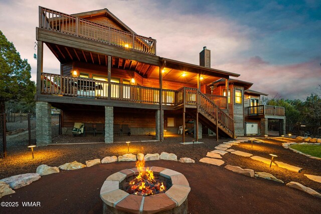 1610 S Canyon Ridge Trl, Show Low, AZ 85901 - back of house at dusk with a fire pit, a chimney, stairway, a balcony, and a wooden deck