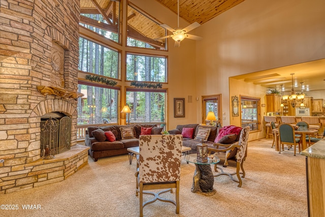 living area with high vaulted ceiling, a stone fireplace, ceiling fan with notable chandelier, wood ceiling, and carpet flooring