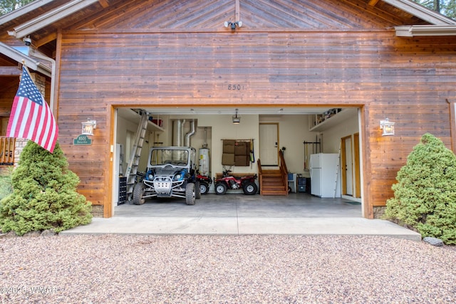 garage with freestanding refrigerator, driveway, and gas water heater