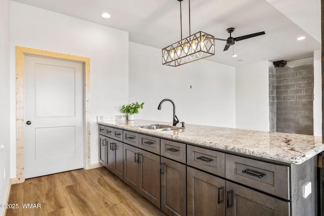 436 E 11th Ln, Eagar, AZ 85925 - kitchen with a sink, a peninsula, light stone countertops, light wood-type flooring, and a ceiling fan