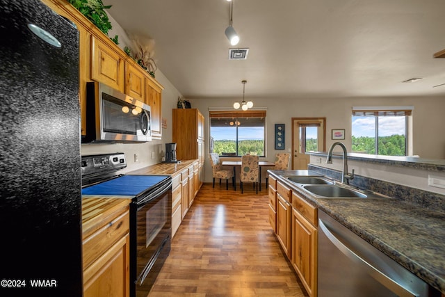 kitchen with decorative light fixtures, a wealth of natural light, visible vents, a sink, and black appliances