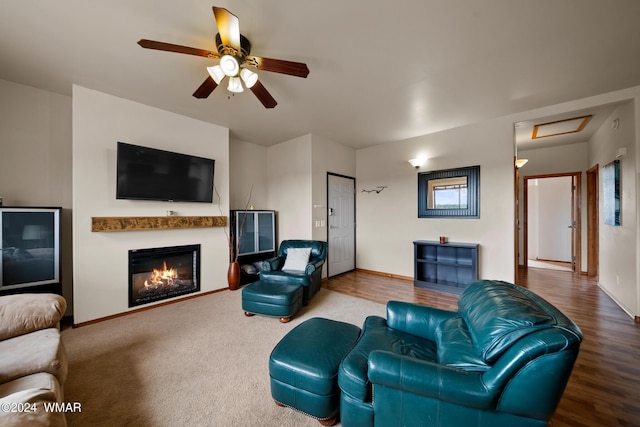 living area featuring attic access, baseboards, ceiling fan, and a glass covered fireplace