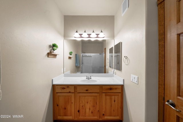 bathroom featuring visible vents, a shower stall, and vanity