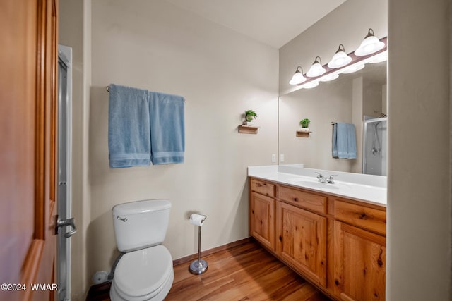 full bath featuring a shower with shower door, wood finished floors, vanity, baseboards, and toilet