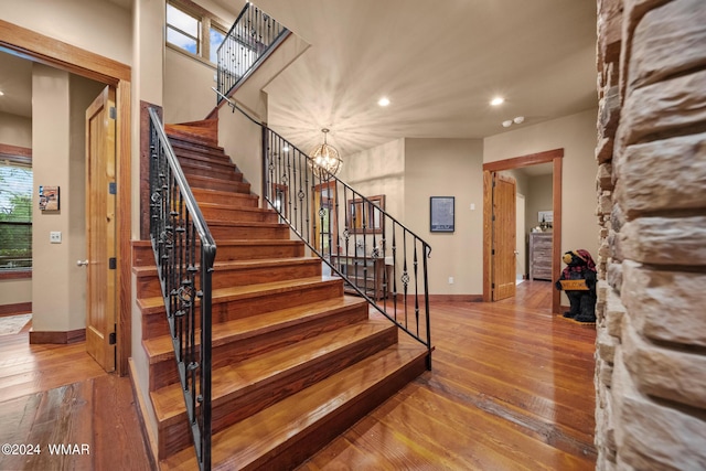 stairs with a notable chandelier, baseboards, hardwood / wood-style floors, and recessed lighting