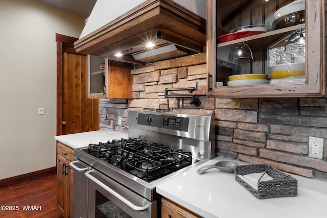 kitchen with light countertops, dark wood-style flooring, stainless steel range with gas stovetop, and custom range hood