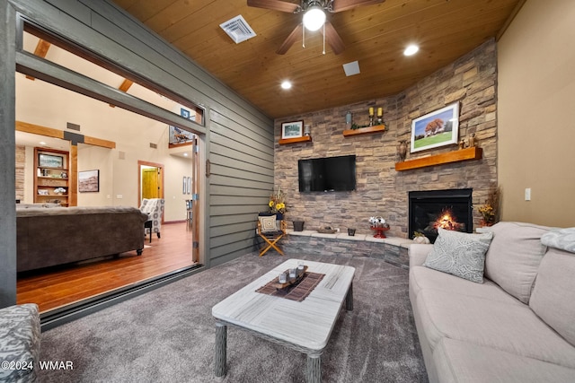 living room with a ceiling fan, wood ceiling, visible vents, and a stone fireplace