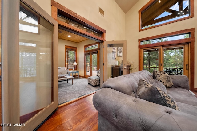 living room featuring wood finished floors, a towering ceiling, visible vents, baseboards, and french doors