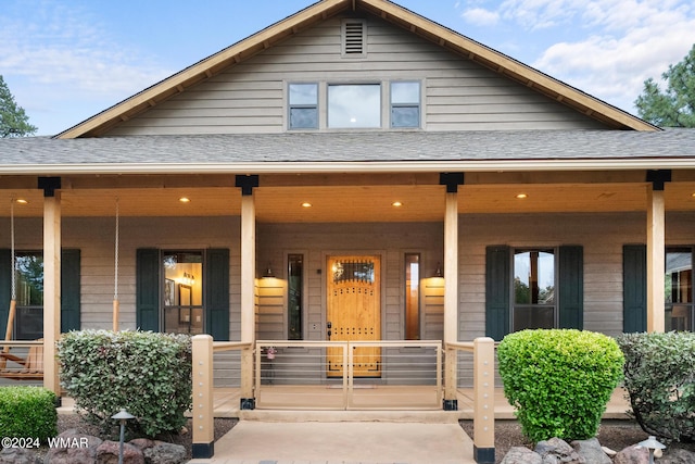 view of front facade with a shingled roof and a porch