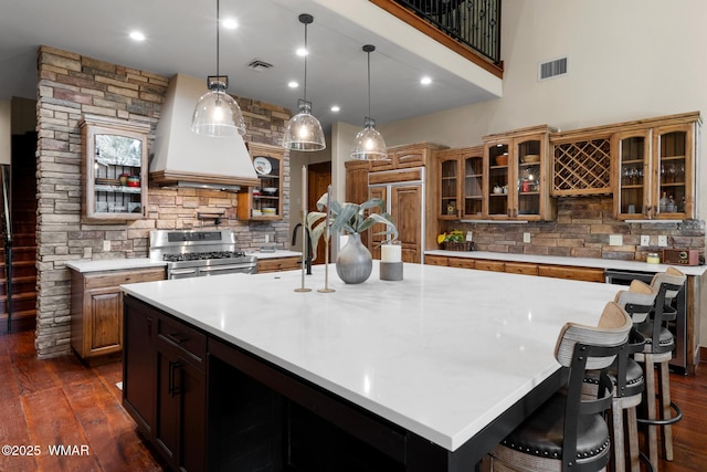 kitchen featuring visible vents, dark wood-style flooring, double oven range, and premium range hood