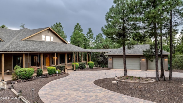 view of front of house featuring a shingled roof, a porch, and decorative driveway