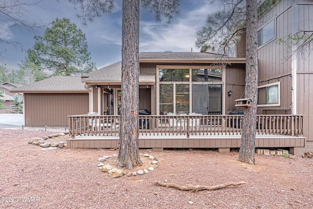 view of front of home with a deck and roof with shingles