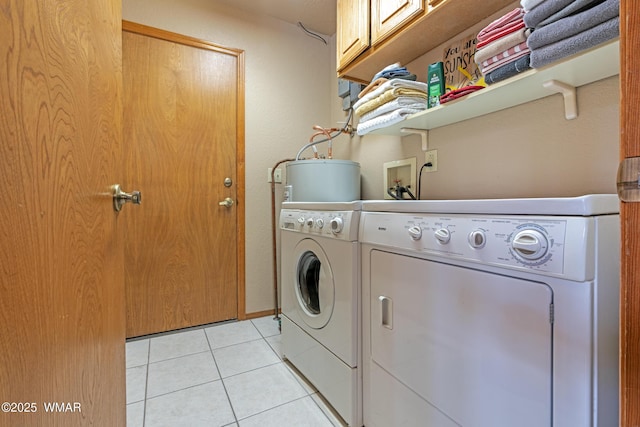 laundry room with washing machine and clothes dryer, water heater, cabinet space, and light tile patterned floors