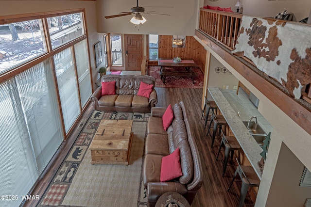 living area with wood finished floors, a towering ceiling, and a ceiling fan