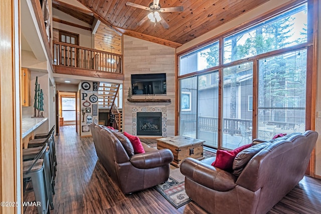 living area with wood ceiling, a large fireplace, a ceiling fan, and dark wood finished floors
