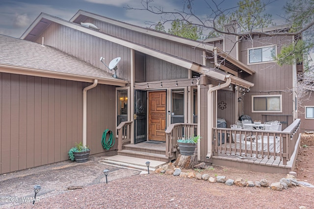 view of exterior entry featuring roof with shingles