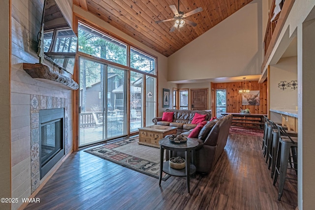 living area with a glass covered fireplace, a wealth of natural light, wood ceiling, and dark wood finished floors
