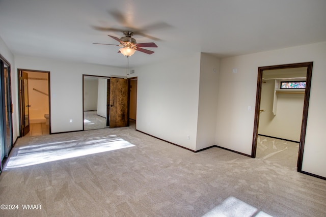 unfurnished bedroom with a walk in closet, a closet, visible vents, light carpet, and baseboards