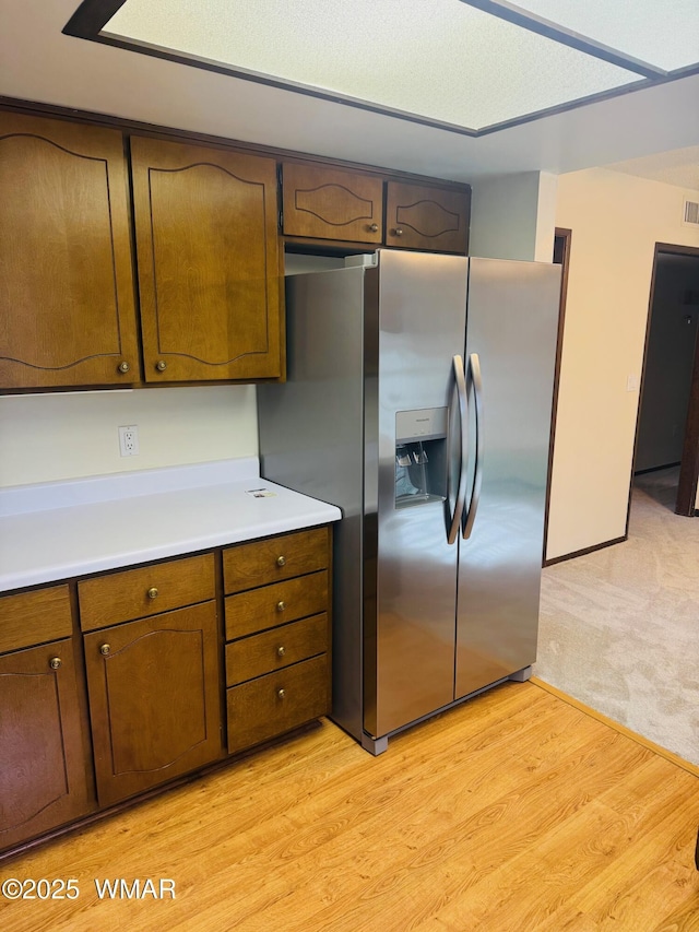 kitchen featuring light wood-style floors, light countertops, stainless steel fridge, and visible vents