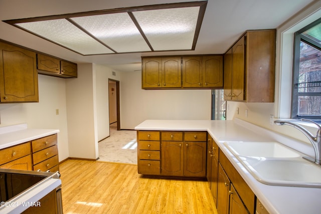 kitchen with light countertops, a sink, and brown cabinets