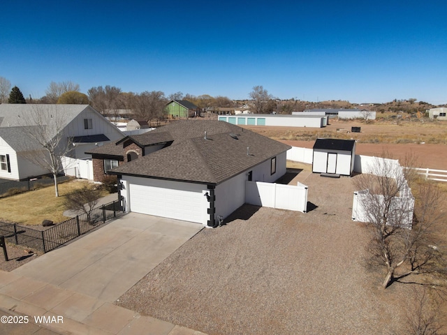 view of front of home with driveway, a shingled roof, a garage, and fence