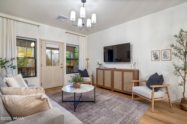 living area featuring visible vents, baseboards, a chandelier, and wood finished floors