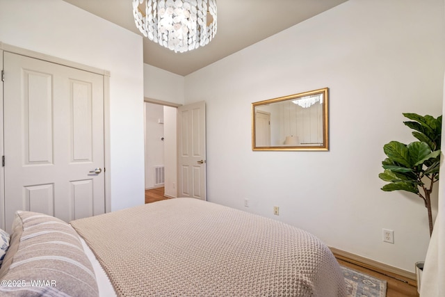 bedroom with visible vents, baseboards, light wood finished floors, and a chandelier
