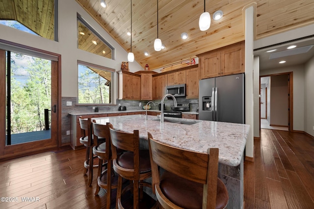 4611 Stonecrop Ln, Show Low, AZ 85901 - kitchen featuring stainless steel appliances, lofted ceiling, decorative light fixtures, a center island with sink, and light stone countertops
